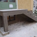 R5-kantsten placerad längs en husgrund, utan trappnos och överhäng. Ytan är borstad och i en grå nyans